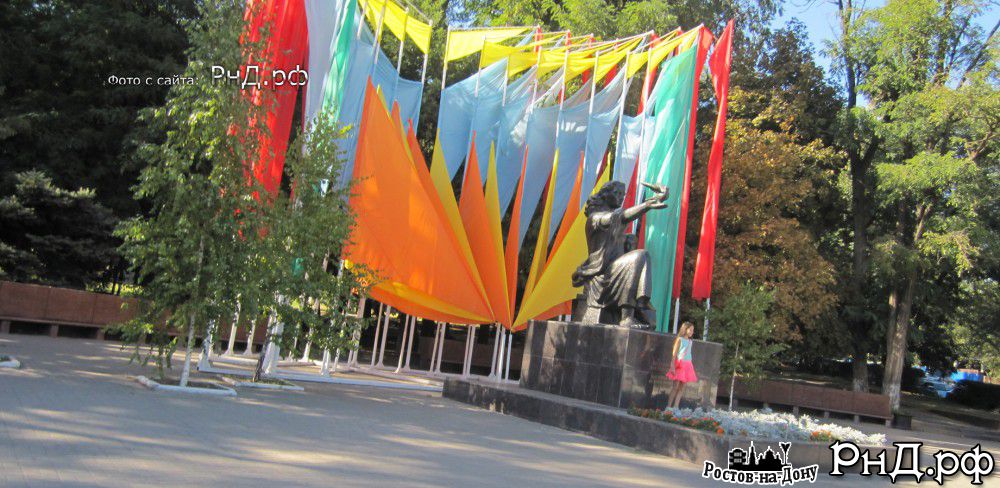 Памятник матери и ребенку на фоне праздничных знамен ко дню города