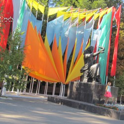 Памятник матери и ребенку на фоне праздничных знамен ко дню города